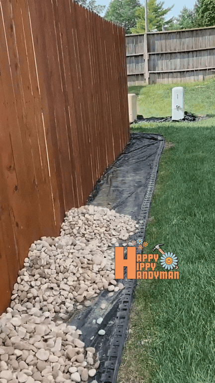 Layering decorative stones along a wooden fence, illustrating practical landscaping solutions for improved drainage and style.